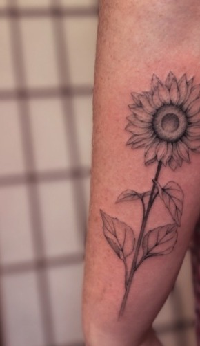 Fine-line sunflower tattoo on the forearm
